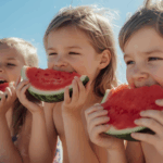 Kids at the beach eating watermelon